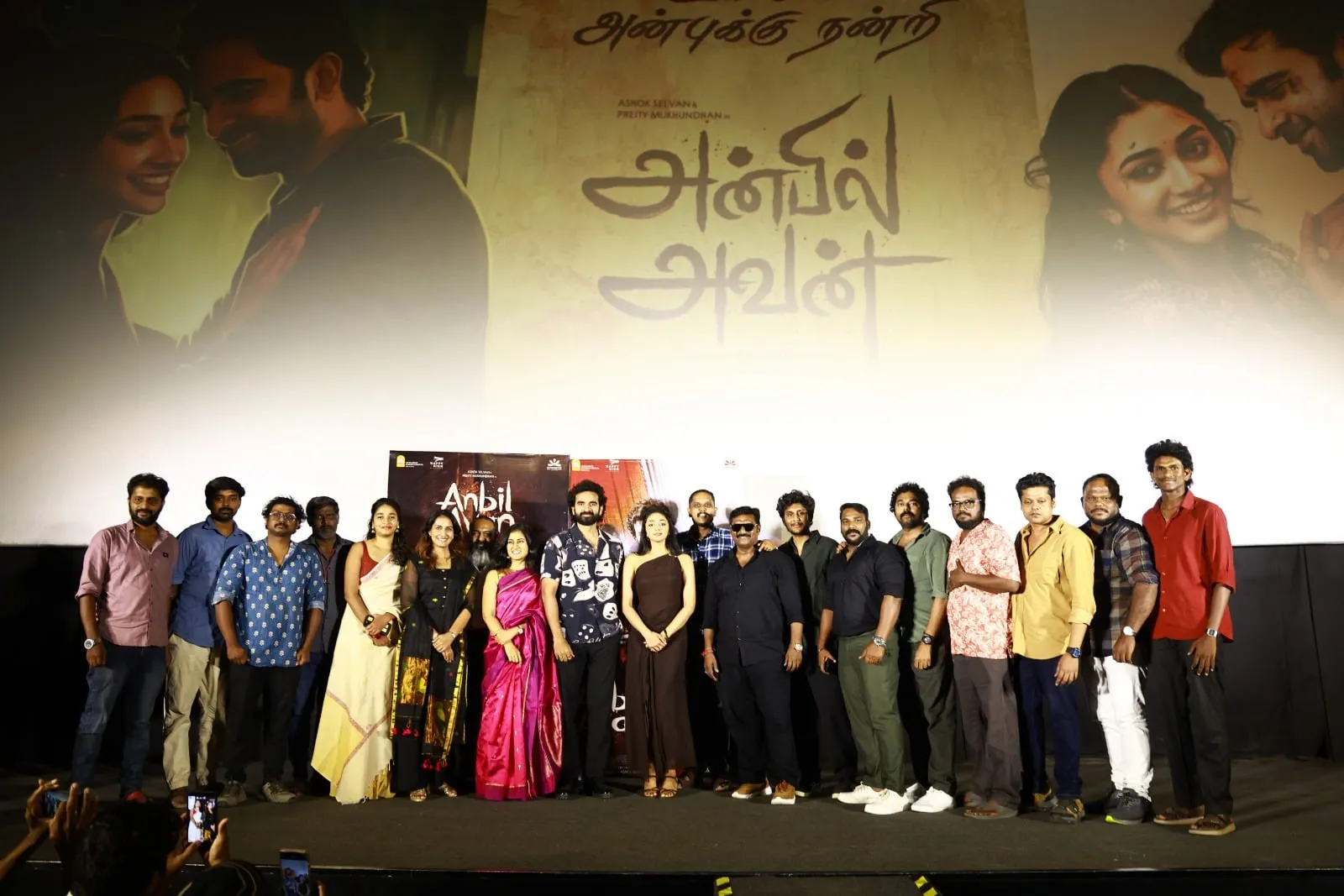 The Anbil Avan cast and crew on stage in front of the film's title on the cinema screen
