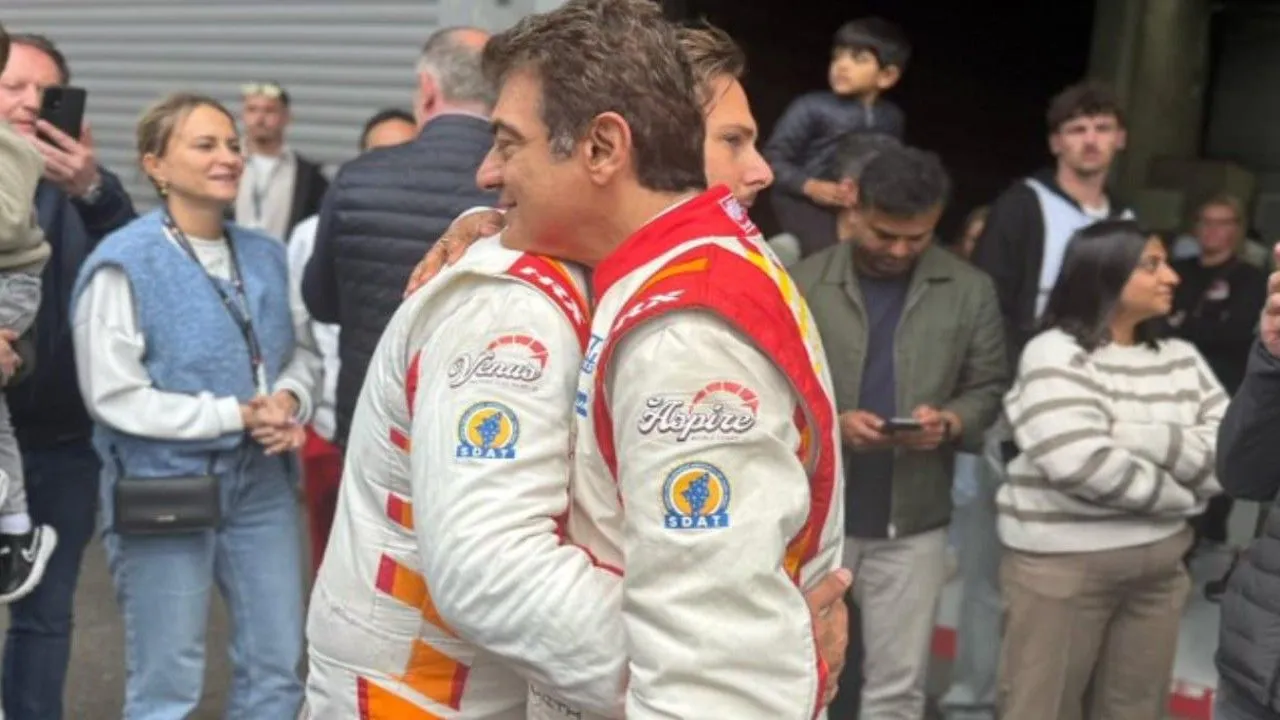 Ajith Kumar in racing overalls celebrating with a teammate at the Circuit de Spa-Francorchamps after his team's P2 podium finish