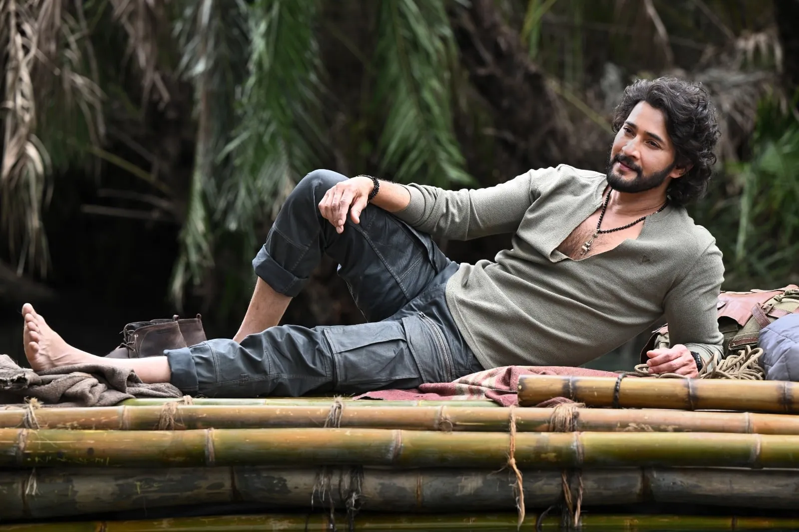 Mahesh Babu as Rudhra resting on a bamboo raft in a dense jungle in Varanasi