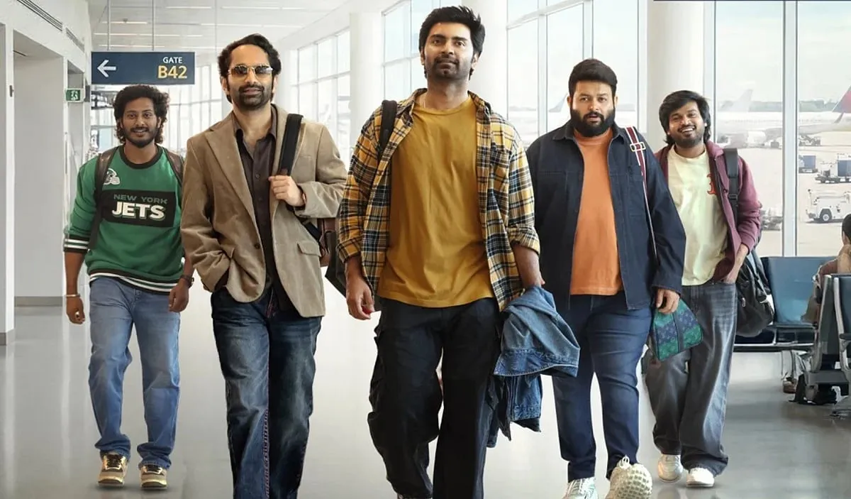 Atharvaa and Fahadh Faasil walking through an airport with friends in a still from Idhayam Murali