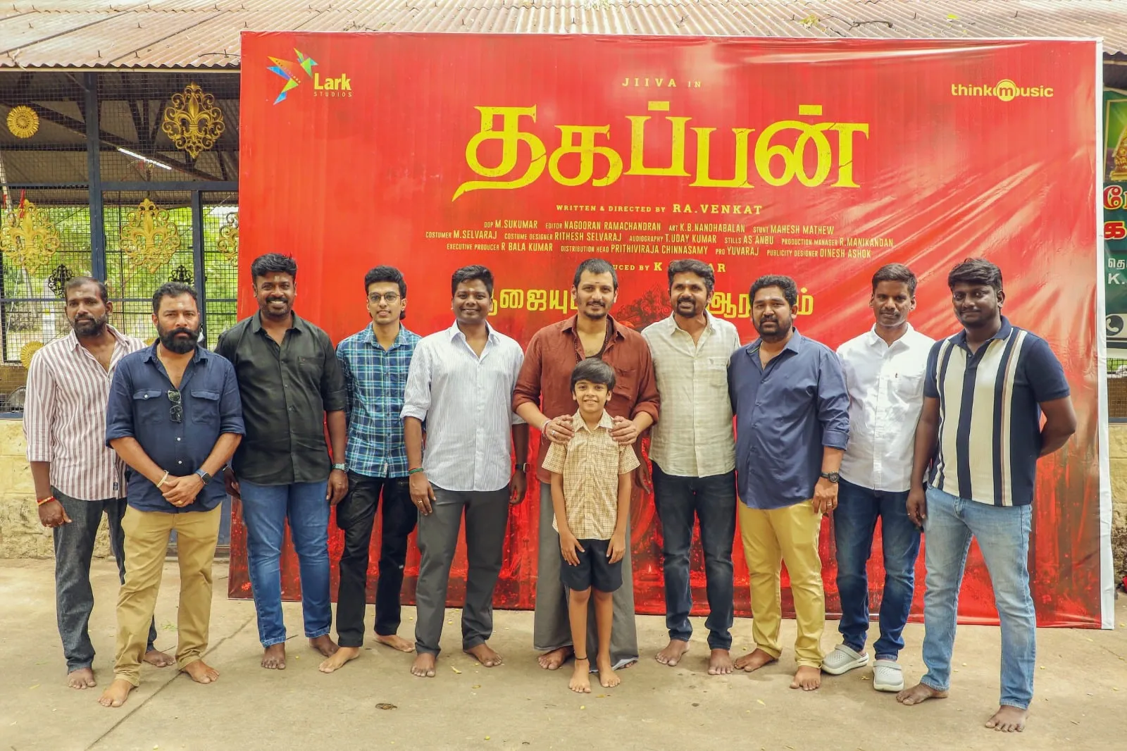 Jiiva with director Ra. Venkat and the Thagappan team in front of the film's title banner in Madurai