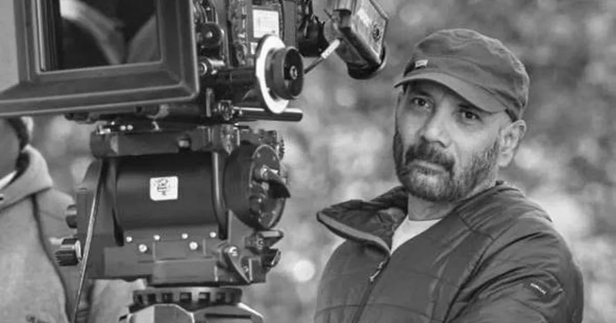 Cinematographer R. Chezhiyan beside a film camera in a black and white photograph
