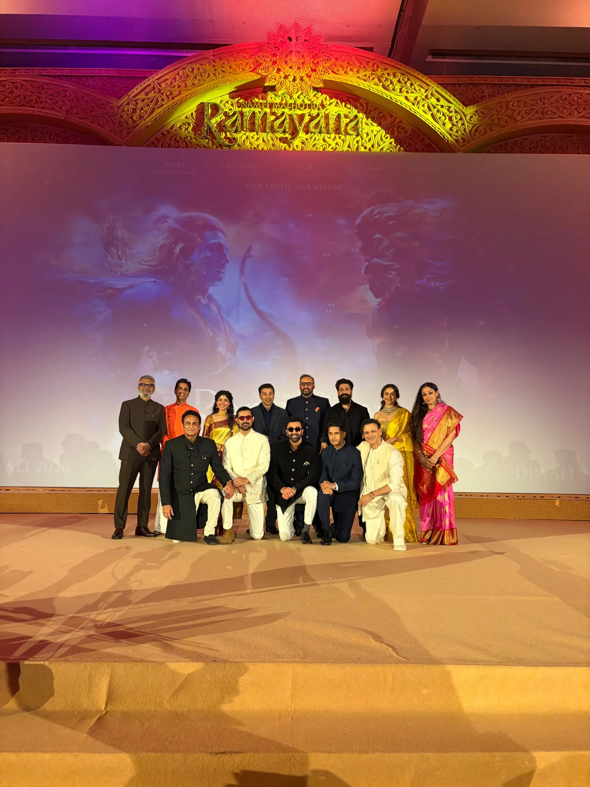 The Pratham Sankalp stage in New Delhi, with the Ramayana ensemble beneath a lit archway and the film's Diwali 2026 release stamped on the backdrop.