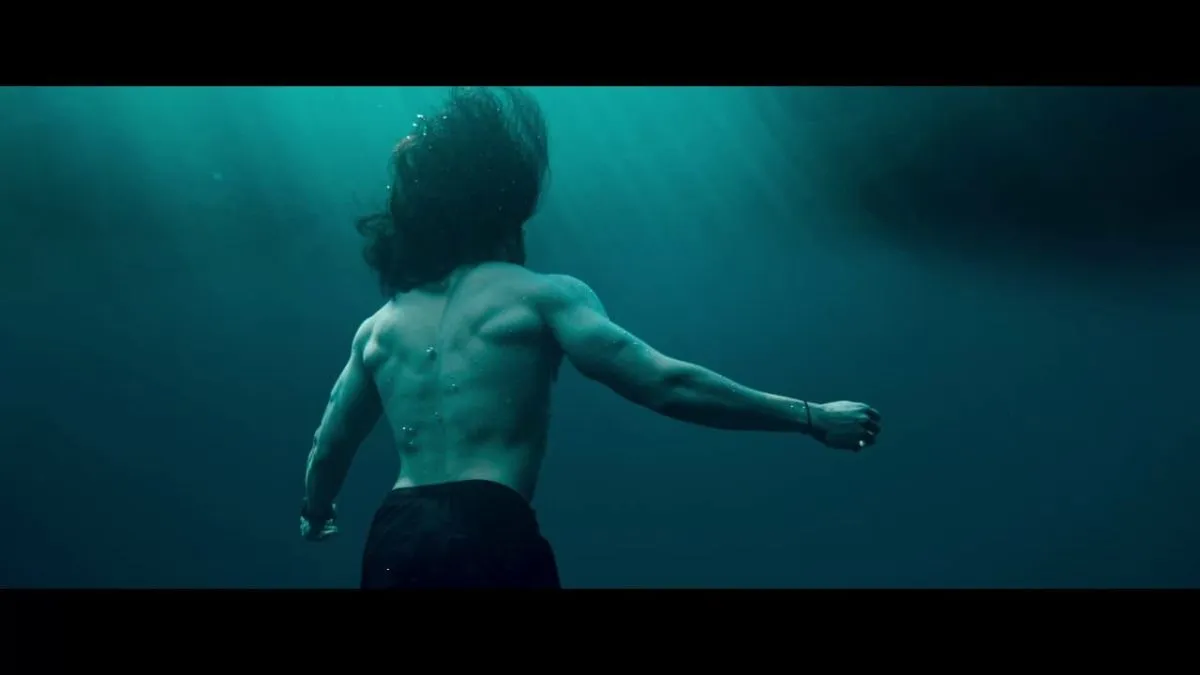Arya underwater with arms spread and light filtering from above in Mr X