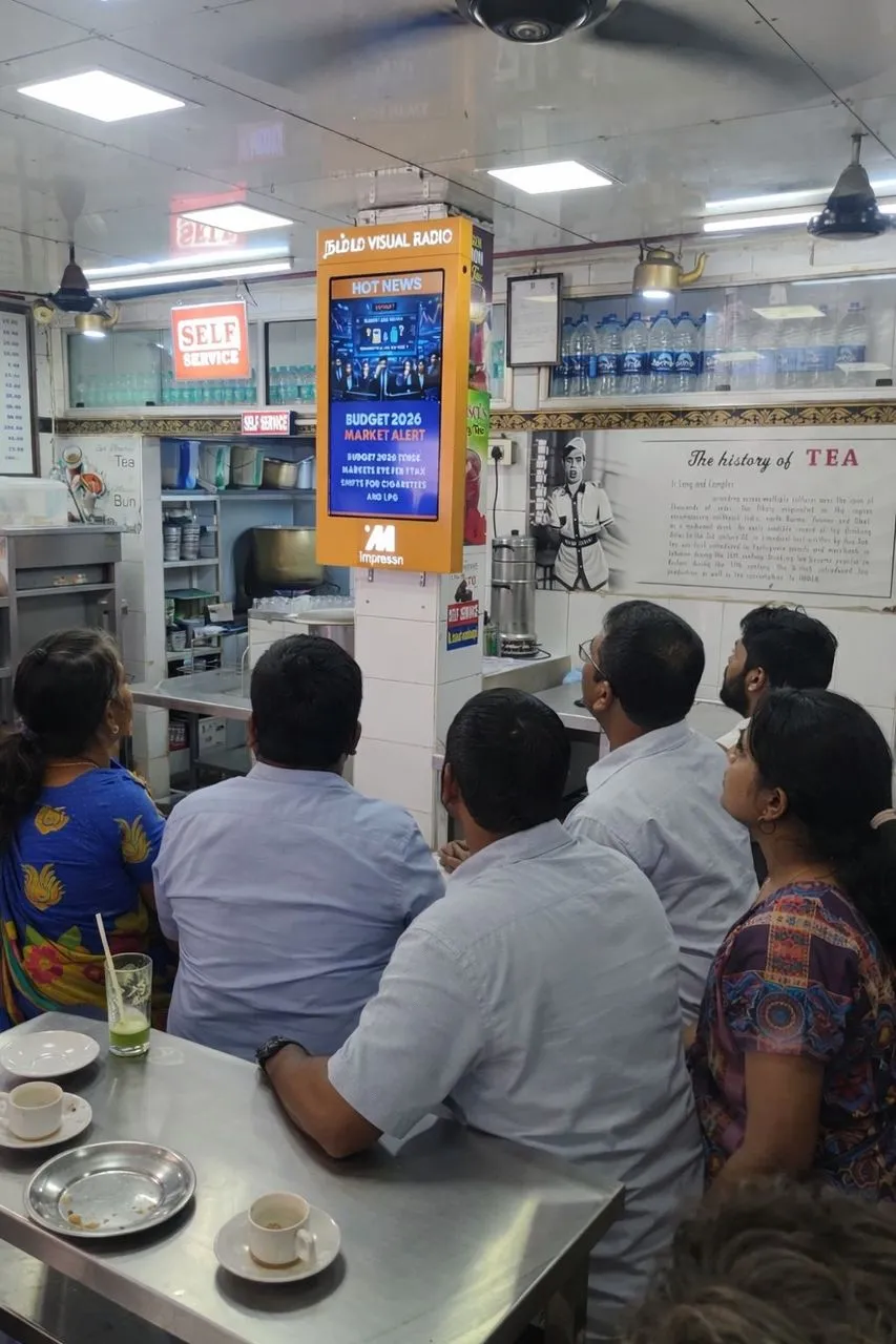 Group of customers watching Budget 2026 news on an Impressn screen at a Chennai tea shop