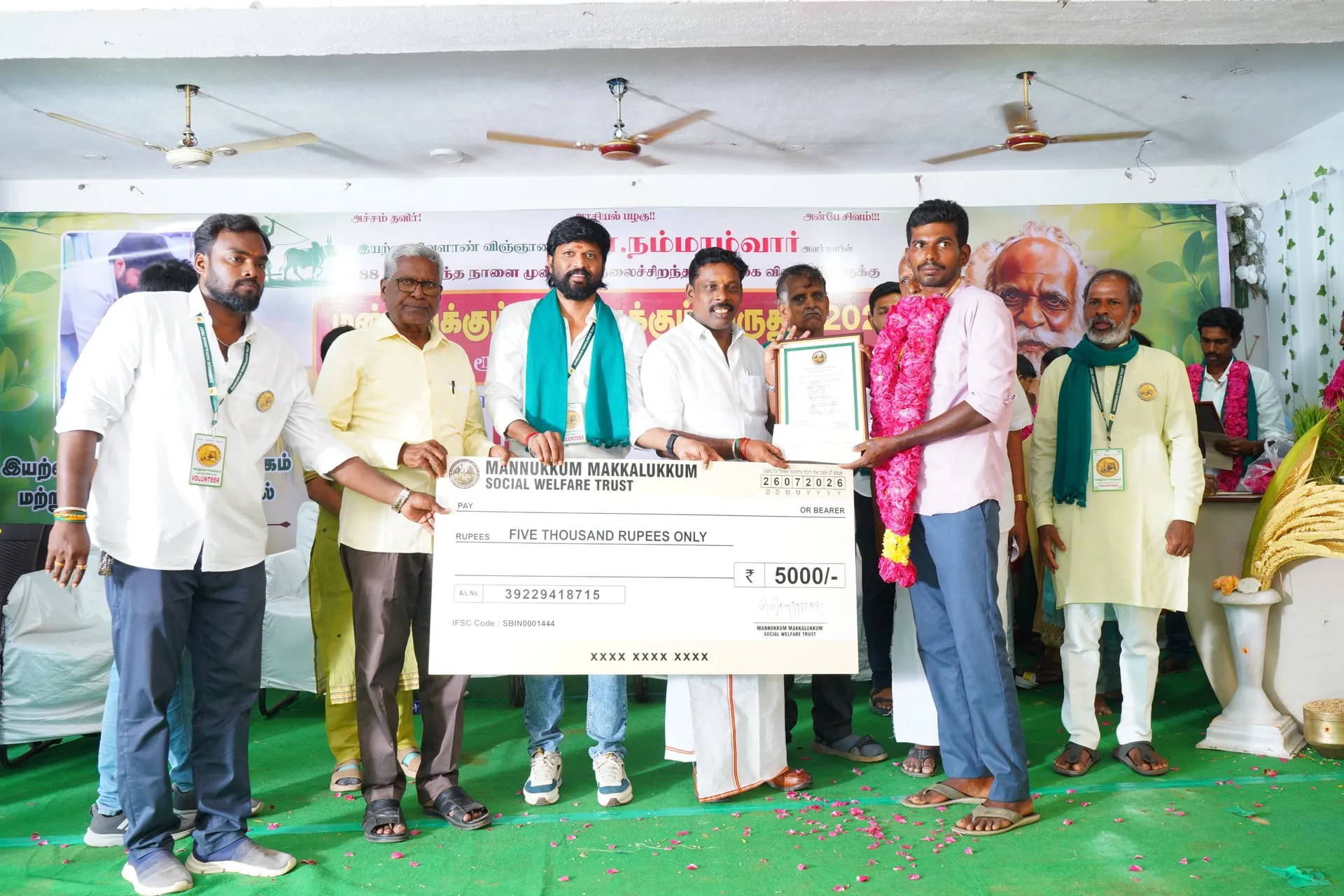 Soundararaja handing over a cheque to one of the honoured farmers