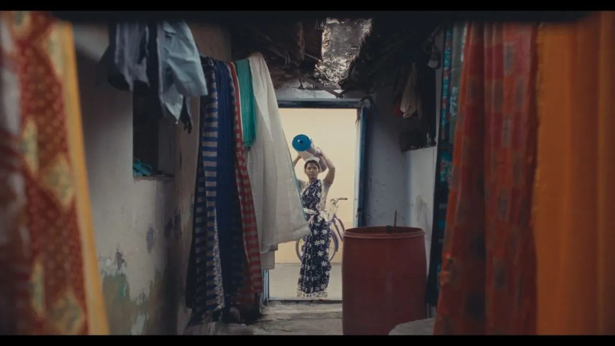 A woman seen through hanging clothes and fabrics in a still from Mayilaa