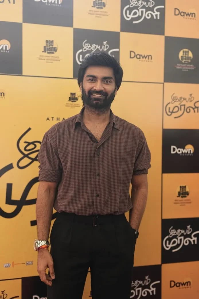 Atharvaa at the Idhayam Murali thanksgiving meet, in front of the film's backdrop